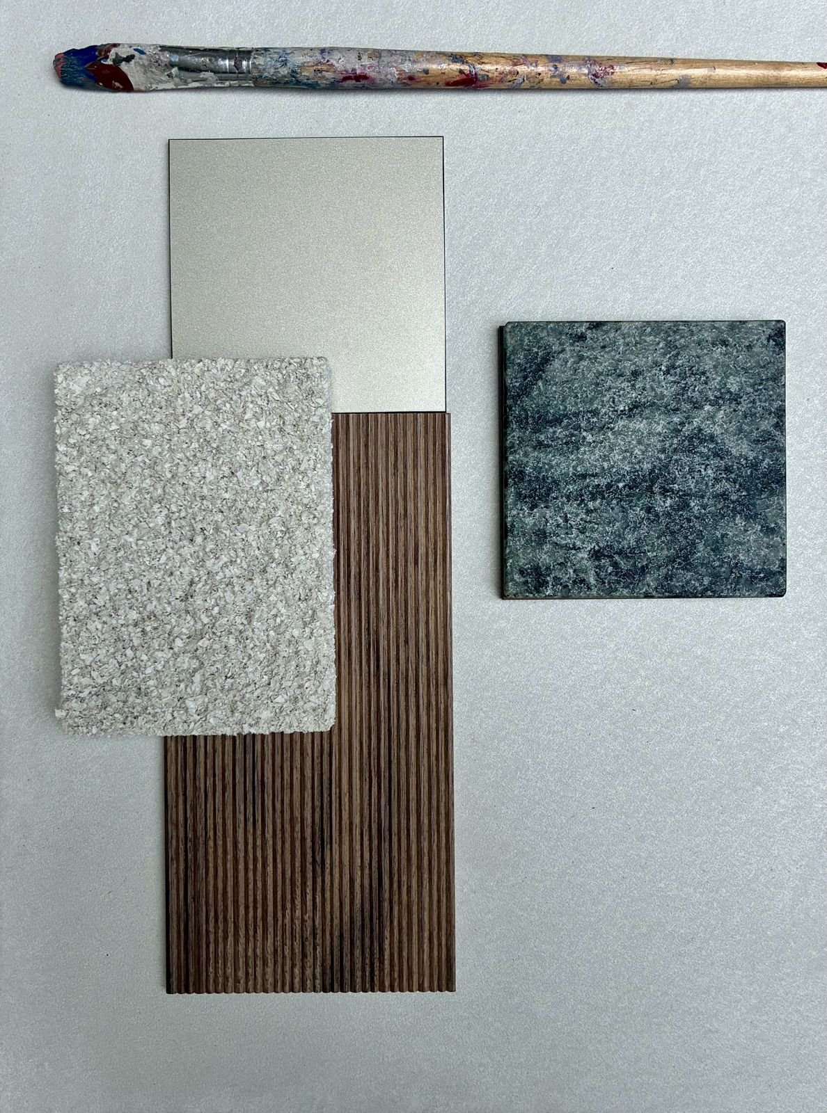 Planche de matières : laiton satiné, bois cannelé, pierre texturée, pierre verte veinée
